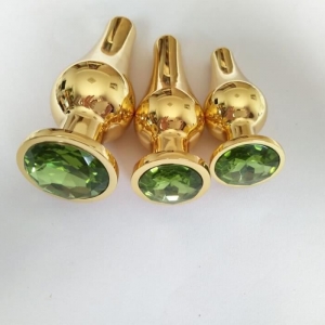 Золотистая удлиненная анальная пробка "Ювелир" Танго с зеленым кристаллом